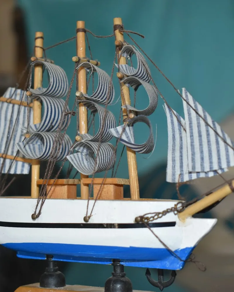 Detalle de los palos, vergas y jarcia de una maqueta de velero con el casco pintado y su línea de flotación.