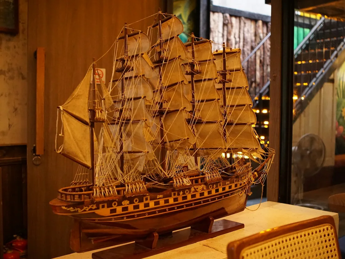 Maqueta de un velero de tres palos con velas de tela y jarcia, apoyada sobre su peana de madera.